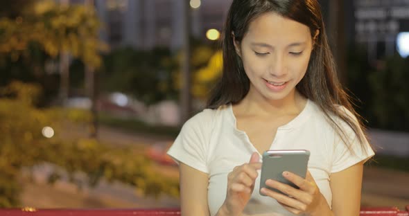 Young woman looking at mobile phone in city at night