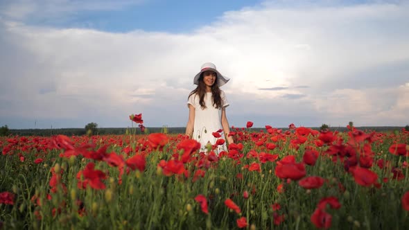 Happy Woman in White Dress and Hat on Poppy Flowers Field at Summer Blue Deep Sky and Clouds