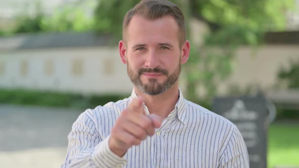 Outdoor Portrait of Middle Aged Man Pointing at Camera Approve