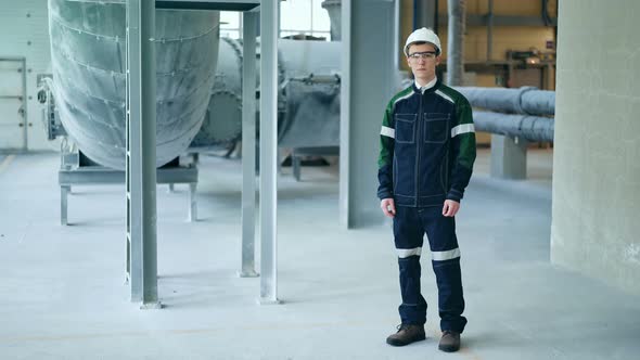 Young Engineer Wearing Protective Helmet Posing Looking at Camera at Modern Factory