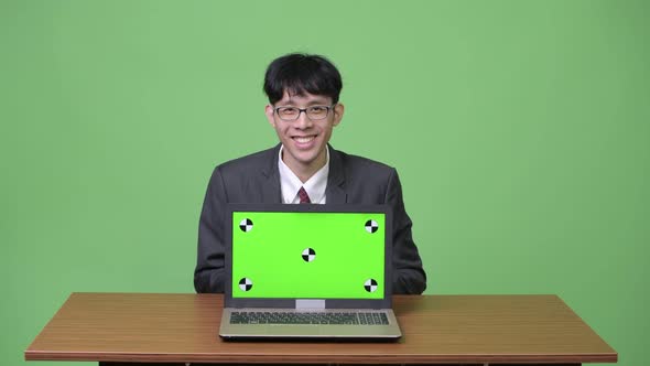 Young Happy Asian Businessman Smiling While Showing Laptop To Camera