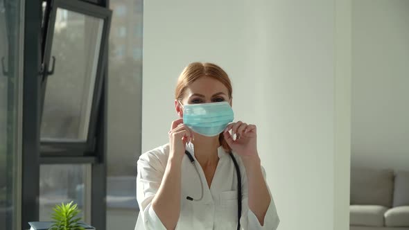 Female Doctor Puts on Medical Mask in Clinic. Health Protection Coronavirus Concept