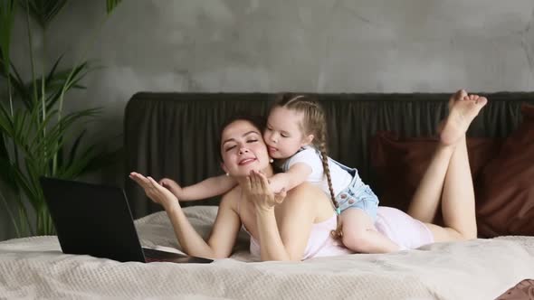 American Woman Having Fun with Little Girl and Using Laptop on Bed at Home Bedroom Iroi