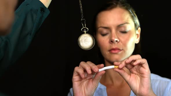 Woman breaking a cigarette in front of a pendulum to stop smoke