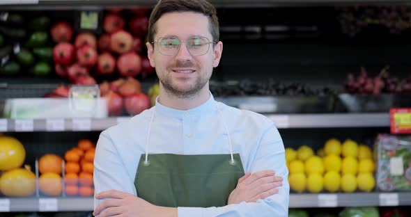 Close Up Portrait of Happy Man Worker in Glasses Wearing Apron Standing in Supermarket and Looking