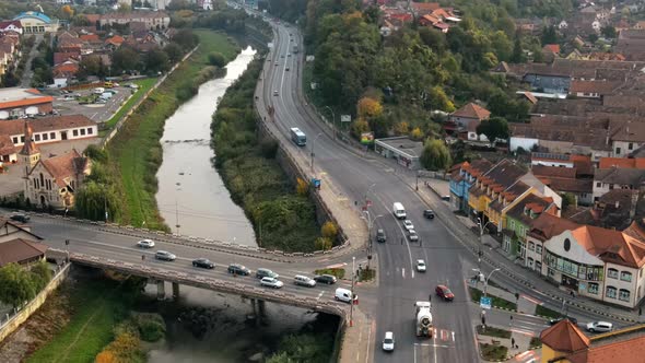 Aerial drone view of Sighisoara, Romania. Roads with cars, river, greenery and buildings