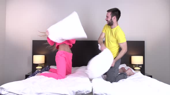 Young Happy Couple Having a Pillow Fight in a Bed