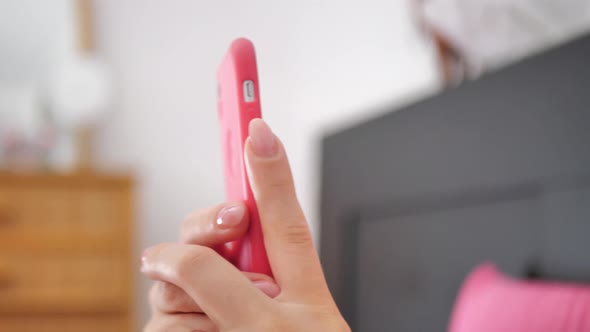 Woman Holding a Pink Phone Looking at Social Networks on It