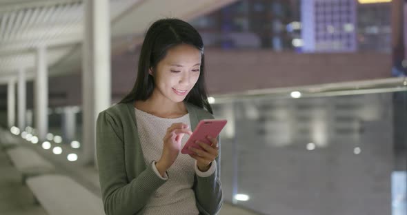 Woman sending message on cellphone in Hong Kong at night