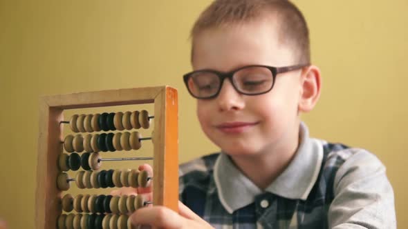 Caucasian boy with a smile in glasses counts on the accounts holding them in front of him