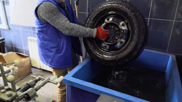 Worker washes a wheel at a tire service
