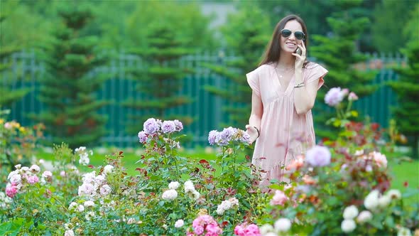 Young Girl in a Flower Garden Among Beautiful Roses. Smell of Roses