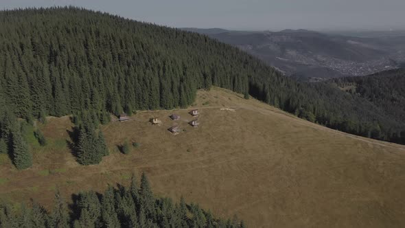 Aerial view of wooden houses on an carpatian meadow among mountains.