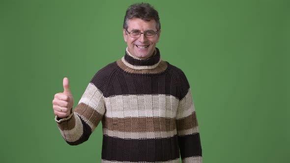 Mature Handsome Man Wearing Turtleneck Sweater Against Green Background