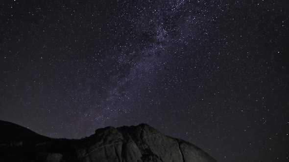 Shimmering Stars and the Milky Way in the Night Sky above High Mountain Rocks