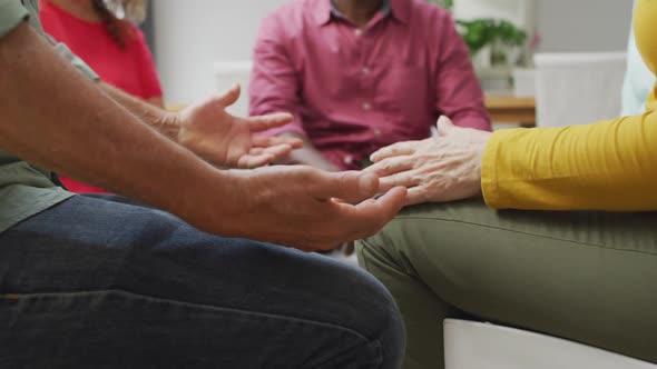 Animation of midsection of diverse seniors holding hands during support group meeting