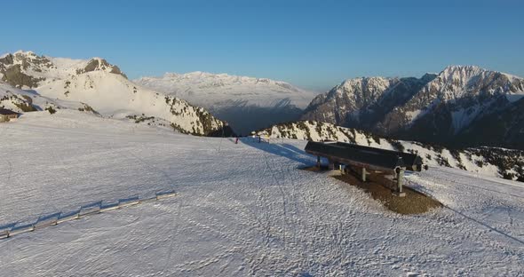 Ski lift station at Chamrousse mountain summit in the French Alps during sunset, Aerial flyover appr