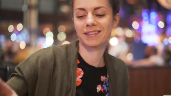 Happy Smiling Woman Laughing and Having Nice Conversation with a Date or Friend. Taking Sip of Red