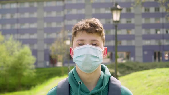 Young student in a medical protective mask with a backpack