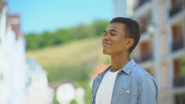 Happy Mixed-Race Male Teen Inhaling Pleasant Bakery Aroma on City Street, Joy