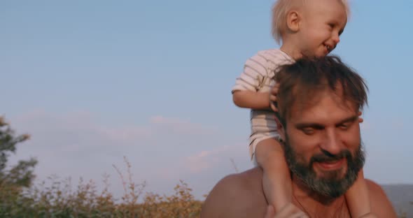 Happy Baby Boy Sits on Bearded Father Neck and Have Fun Together Outdoor