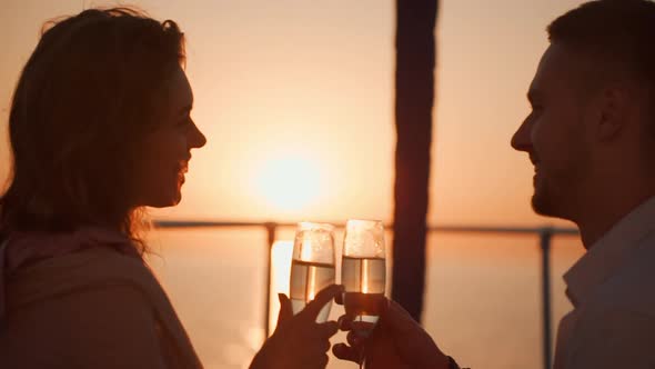 Beautiful Loving Couple Drinking Champagne with Smile on Yacht Looking at Sunrise Together Slow