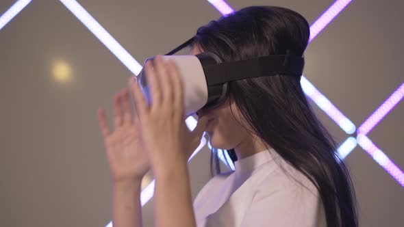 Side View of Surprised Young Woman in 3D-glasses Looking at Hands in Virtual Reality. Excited