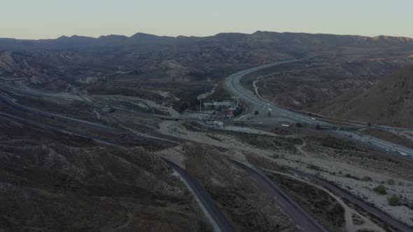 AERIAL: Over Highway in California Countryside with Mountains at Sunset 