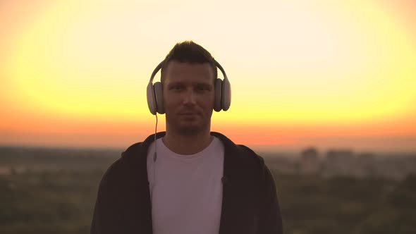 Smiling and Laughing Handsome Young Man Listening Music From His Smartphone in Wireless Headphones