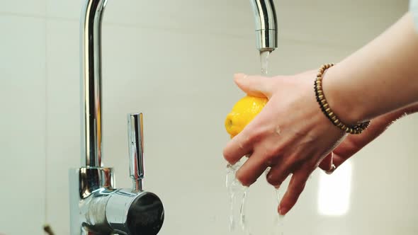 Woman's Hands Wash a Lemon Under the Tap with Water