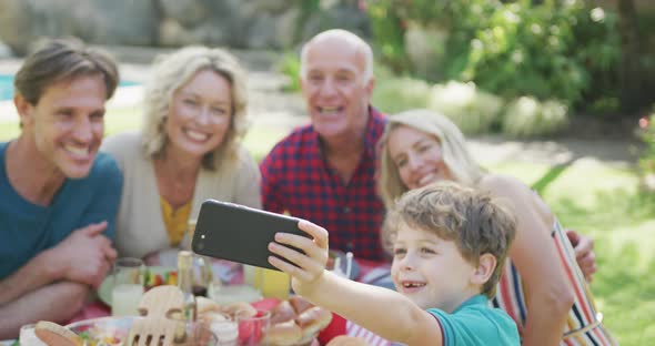 Happy caucasian family having dinner and taking selfie in garden