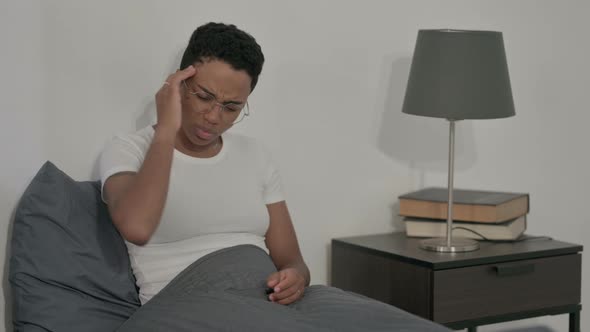 African Woman Having Headache While Sitting in Bed