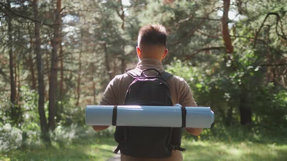 Happy Asian Man with Backpack Walking on Path Forest