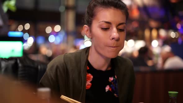 çWoman Eating Delicious Food with Chopsticks While Chatting with Friend