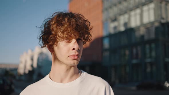 Young Man Stands on Street Looking with Serious Expression