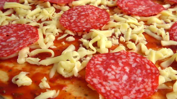 Spinning pizza with mozzarella cheese, tomatoes, tomato sauce and salami.