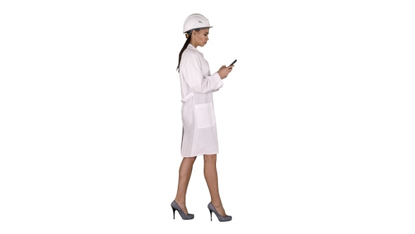 Engineer using mobile phone texting while walking on white