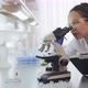 Female chemist looking through microscope - VideoHive Item for Sale