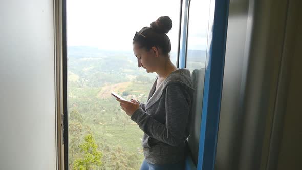 Young Woman Rides on Passenger Railway Transport and Writes Text Message on Mobile Phone. Beautiful