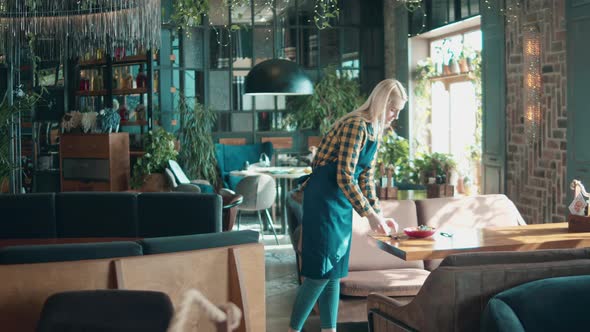 Blond Waitress Smiles After Putting a Dish on the Table