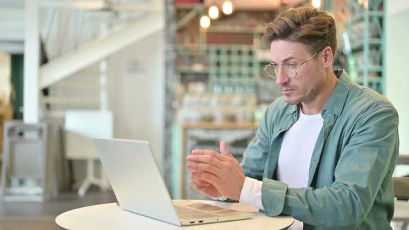 Pensive Middle Aged Man Thinking and Working on Laptop in Cafe 