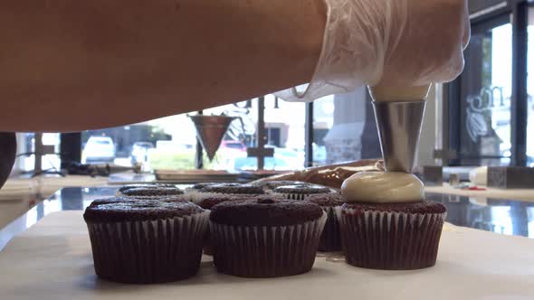A Chef Piping Cupcakes in a Bakery During the day time.