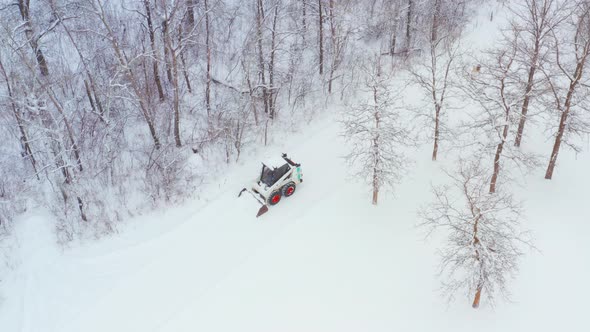 Clearing snow on a rural property with a wheeled bobcat