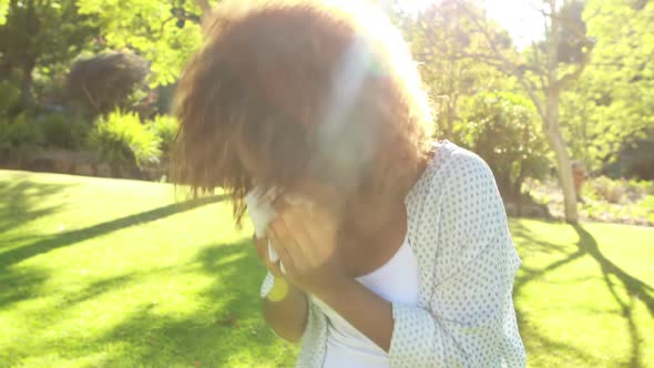 Woman blowing nose in park