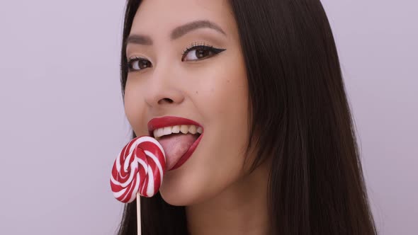 Fashion Portrait of Asian Woman with Lollipop in Studio