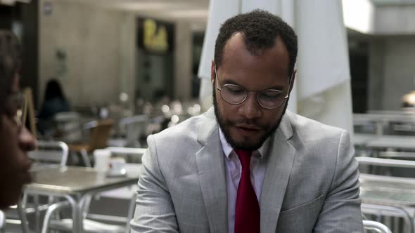 Confident Bearded Businessman Talking with Partner at Cafe