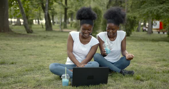 African American Students Sitting in Park with Laptop