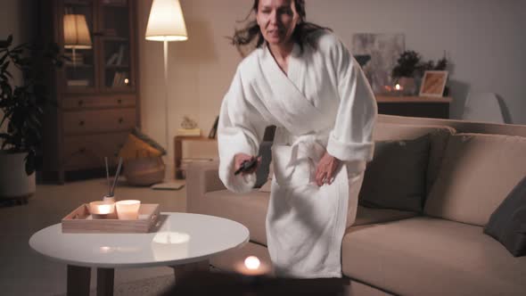 Woman In Bathrobe Watching TV In Evening