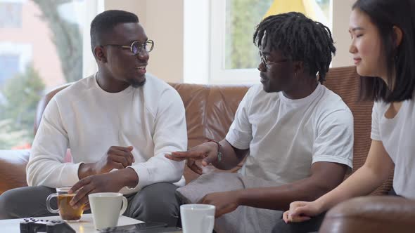 African American Millennial Men Talking Gesturing in Slow Motion Smiling Sitting with Asian Woman