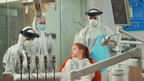 Dentistry Nurse in Coverall Putting Dental Bib to Child Before Examination